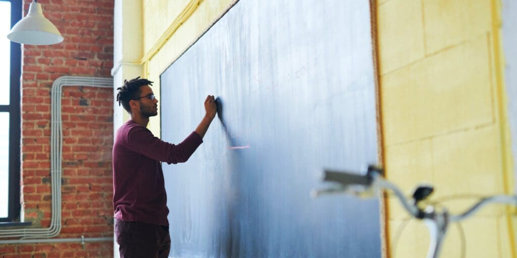 Teacher writing alone on chalkboard