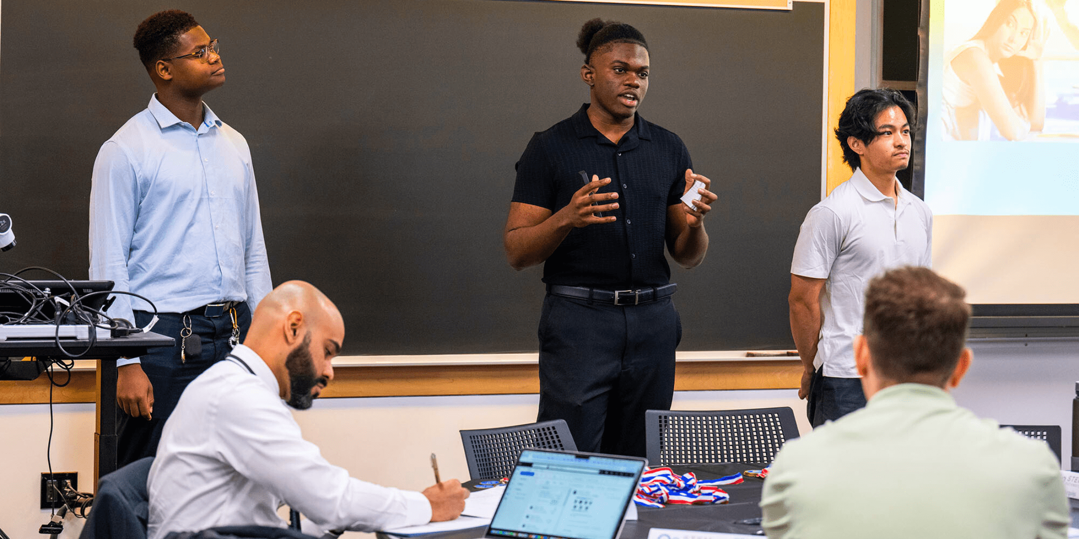 [New Mission High School seniors (from left) Darareaksmey Chhim, Mario Fils, and Dorian Planto present their innovative idea for plastic-consuming bacteria at the Synthetic Biology Shark Tank Competition held at BU's Biological Design Center on April 26, 2024. CREDIT: Boston University]